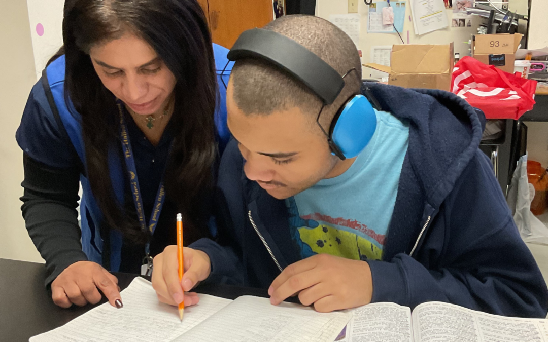 A teacher working one-on-one with a student in a calm, supportive classroom environment at The Hallen School.